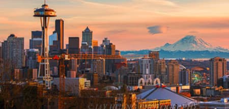 Seattle skyline at sunset with the Space Needle and Mount Rainier in the distance.