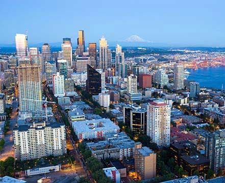 Elevated view of the Seattle skyline with skyscrapers, Elliott Bay, and Mount Rainier.